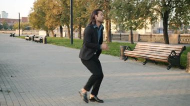 Modern şehirde dans eden heyecanlı adamın yavaş çekim portresi. Yaz gününün tadını çıkar.