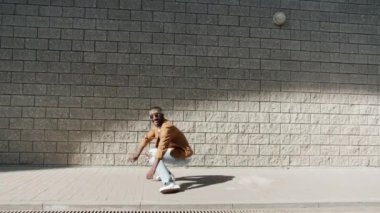 Güneşli bir günde şehrin dışında sahne alan yetenekli Afro-Amerikan break dansçısının portresi.