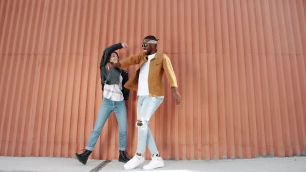 Feliz pareja de raza mixta caminando haciendo high-five luego bailando al aire libre en la calle — Vídeo de stock