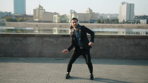 Långsam rörelse porträtt av glada entreprenör bär hörlurar dansar mot urban bakgrund — Stockvideo