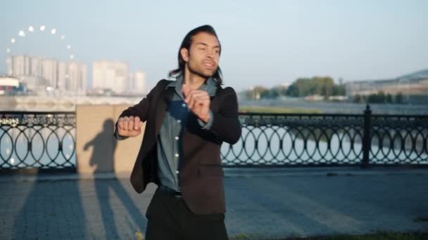 Retrato de empresario alegre bailando afuera en el terraplén del río en la ciudad moderna — Vídeo de stock