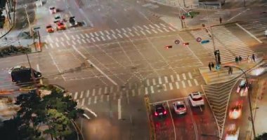 Şehir kavşağında gece dinamik trafik akışı, yaya geçitlerinde gezinen araçlar ve olay yerini aydınlatan trafik işaretleri görülüyor. Zaman aşımı, Seul, Güney Kore