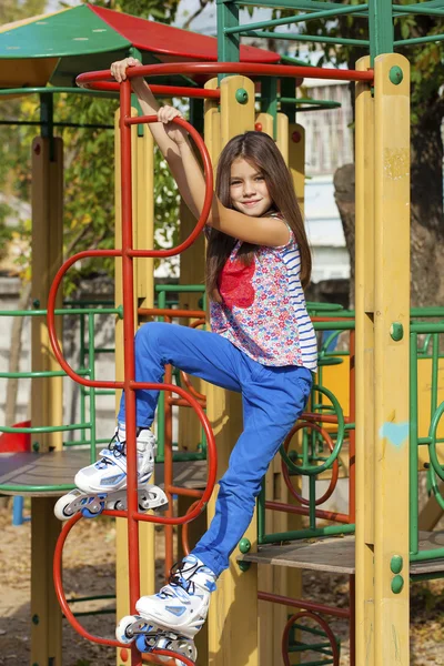 Kleines Mädchen sitzt mit Rollschuhen auf Spielplatz — Stockfoto