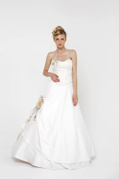 Porträt einer hinreißenden Braut im Brautkleid über grauem Rücken — Stockfoto