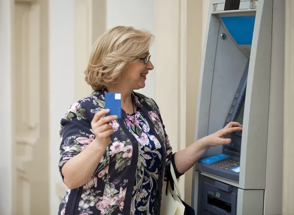 Mature blonde woman counting money near ATM — Stock Photo, Image