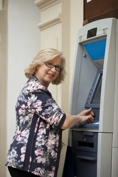 Femme blonde mature comptant l'argent près de guichet automatique — Photo