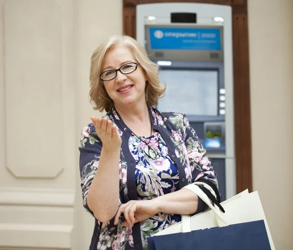 A elderly woman with shopping blonde is on the background in sh — стоковое фото