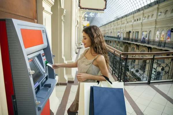 Brunette jonge dame met behulp van een automatische telmachines. vrouw intrekking van geld of betaalrekening evenwicht — Stockfoto