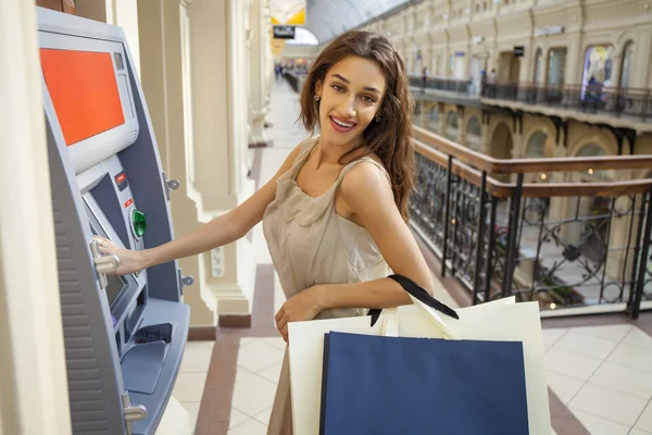 Young happy brunette woman withdrawing money from credit card at — Stock Photo, Image