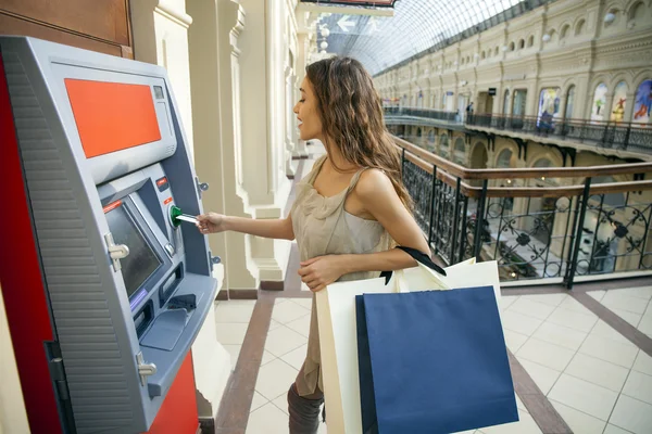 Jovem mulher morena feliz retirando dinheiro do cartão de crédito em — Fotografia de Stock