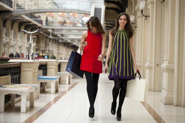 Dos mujeres jóvenes caminando con las compras en la tienda —  Fotos de Stock