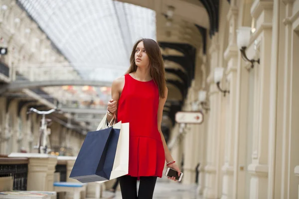 Jonge vrouw in rode jurk wandelen in de winkel — Stockfoto