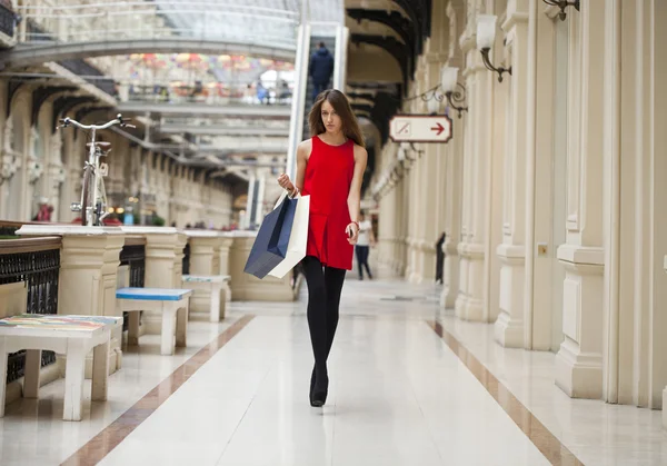 Jovem mulher de vestido vermelho andando na loja — Fotografia de Stock