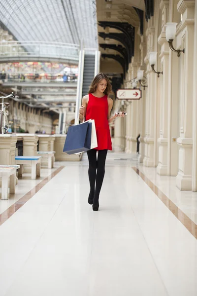 Young woman in red dress walking in the shop — Stock Photo, Image