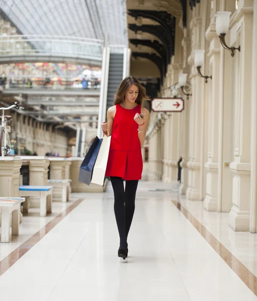 Belle jeune femme tenant des sacs à provisions marchant dans le magasin — Photo