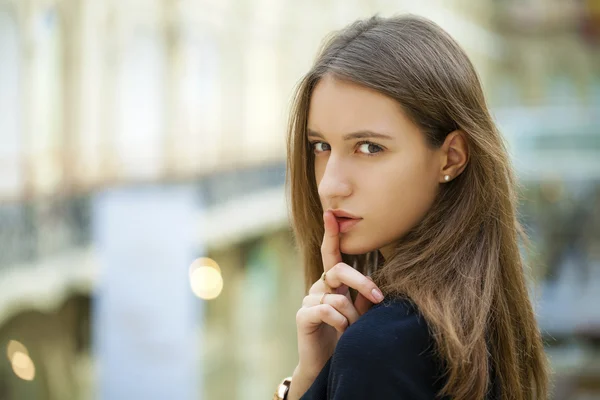 Retrato de una atractiva mujer de pelo joven con el dedo en los labios — Foto de Stock