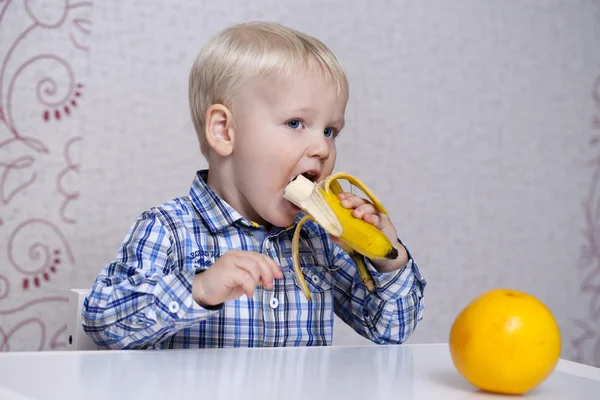 Beautiful little baby boy eats banana — Stock Photo, Image