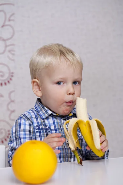 Beautiful little baby boy eats banana — Stock Photo, Image