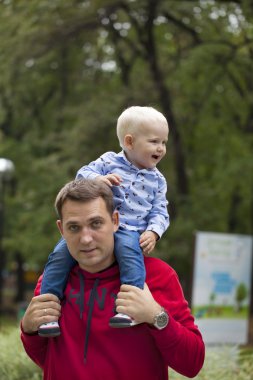 Genç bir baba omuzlarında oturan küçük çocuk