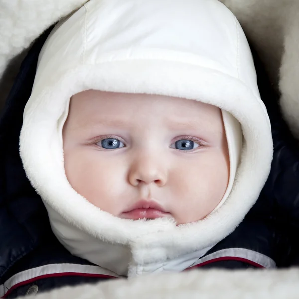 Niño está acostado en un cochecito con ropa de invierno —  Fotos de Stock