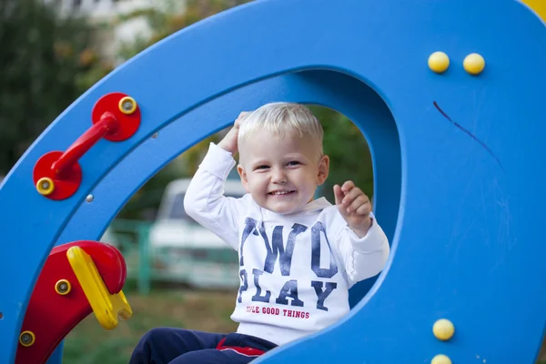 Маленький трехлетний мальчик играет на детской площадке — стоковое фото