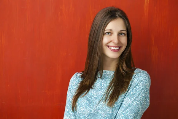 Portrait of a beautiful young woman in a turquoise dress on red — Stock Photo, Image