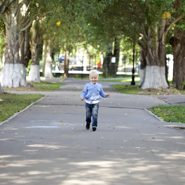 Mały chłopiec biegną na chodniku w parku lato — Zdjęcie stockowe