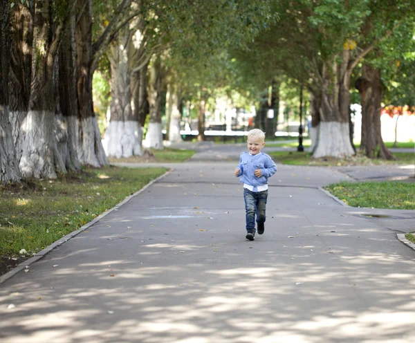 Petit garçon courant sur le trottoir dans le parc d'été — Photo