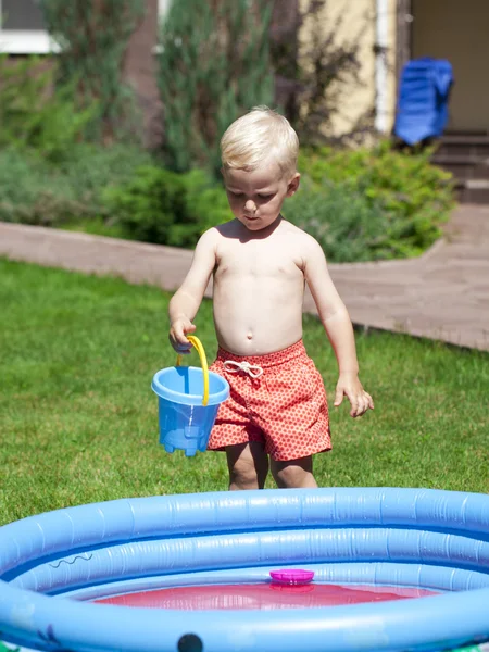 Bambino che gioca con l'acqua vicino alla piscina per bambini sulla la — Foto Stock