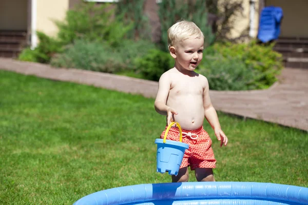 Маленький мальчик играет с водой рядом с детским бассейном на Ла — стоковое фото