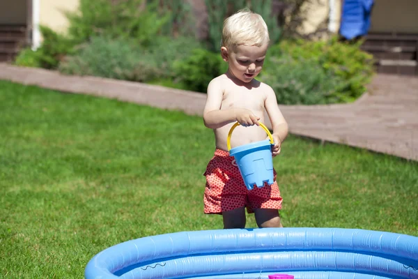 Mały chłopiec bawi się wody w pobliżu basenu dla dzieci na la — Zdjęcie stockowe