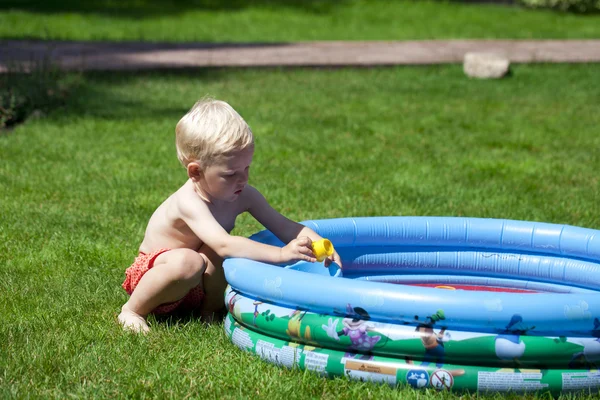 Bambino che gioca con l'acqua vicino alla piscina per bambini sulla la — Foto Stock