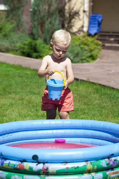 Lille dreng leger med vand nær børnebassinet på la - Stock-foto
