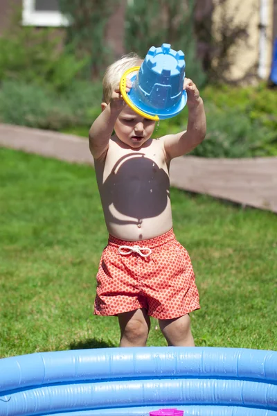 Petit garçon jouant avec l'eau près de la piscine pour enfants sur la la — Photo