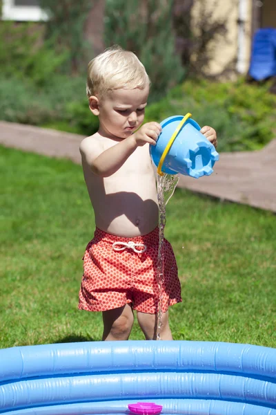 Kleine jongen spelen met water in de buurt van het kinderbad aan de la — Stockfoto