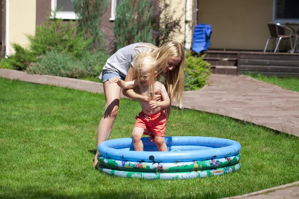 Ung mor med et barn i nærheden af en gummibørnepool - Stock-foto