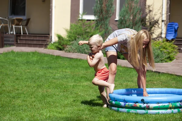 Ung mamma med ett barn nära en gummi barnpool — Stockfoto