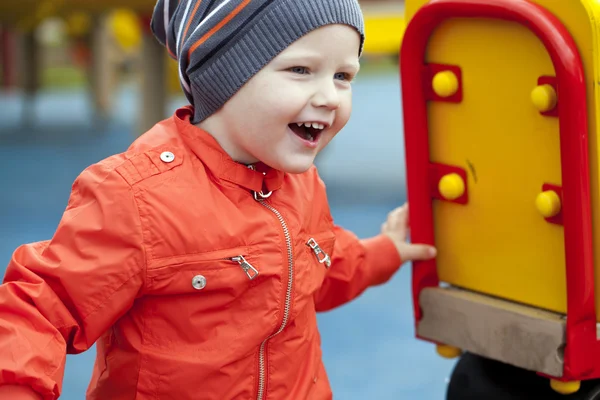 Little boy playing on the playground in the autumn park — Stock Photo, Image