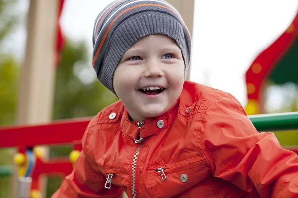 Menino brincando no playground no parque de outono — Fotografia de Stock