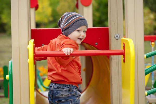 Little boy playing on the playground in the autumn park — Stock Photo, Image