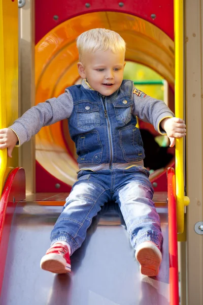 Blond liten pojke sitter på en barnens bild på lekplatsen — Stockfoto