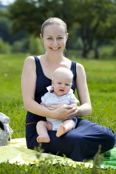 Omtänksam mor håller barnet, mot sommaren park — Stockfoto
