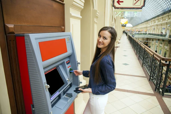 Junge glückliche brünette Frau hebt Geld von der Kreditkarte ab — Stockfoto