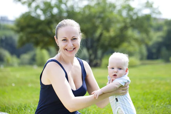 Mère attentionnée tient le bébé, contre le parc d'été — Photo