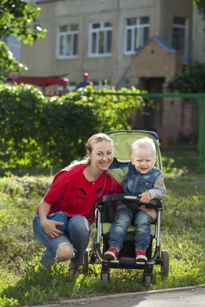 Mały chłopiec siedzi na wózku inwalidzkim i chodzenie z matką — Zdjęcie stockowe