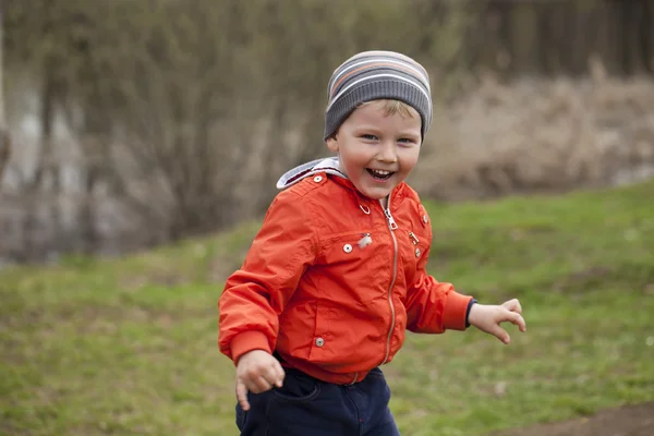 Baby boy in orange jaket and blue jeans — Stock Photo, Image