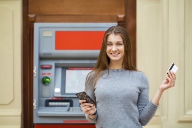 Young happy brunette woman withdrawing money from credit card at clipart