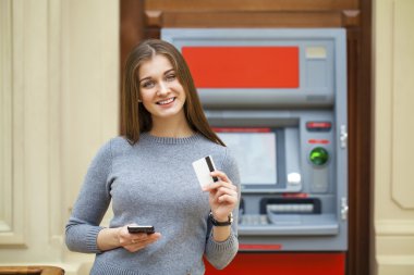 Young happy brunette woman withdrawing money from credit card at clipart