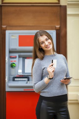 Genç mutlu esmer kadın kredi kartından para çekme