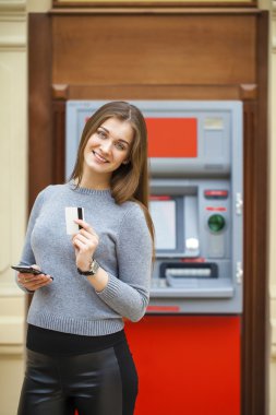 Genç mutlu esmer kadın kredi kartından para çekme